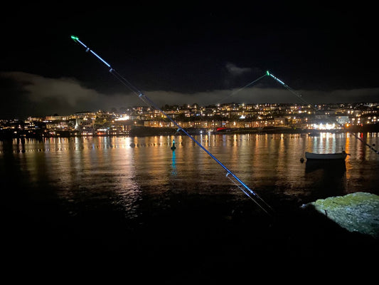 Night fishing in Cornwall, two rods with light tips over looking the water